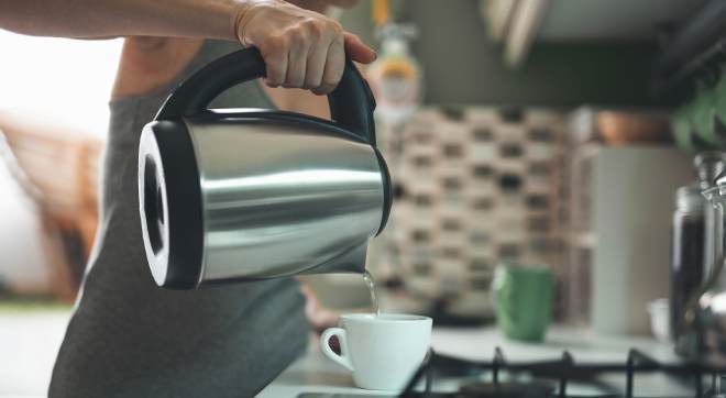 Wasserkocher mit dem Wasser in eine Tee-Tasse gefüllt wird