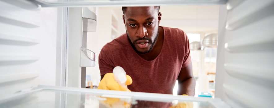 Mann reinigt den Kühlschrank innen